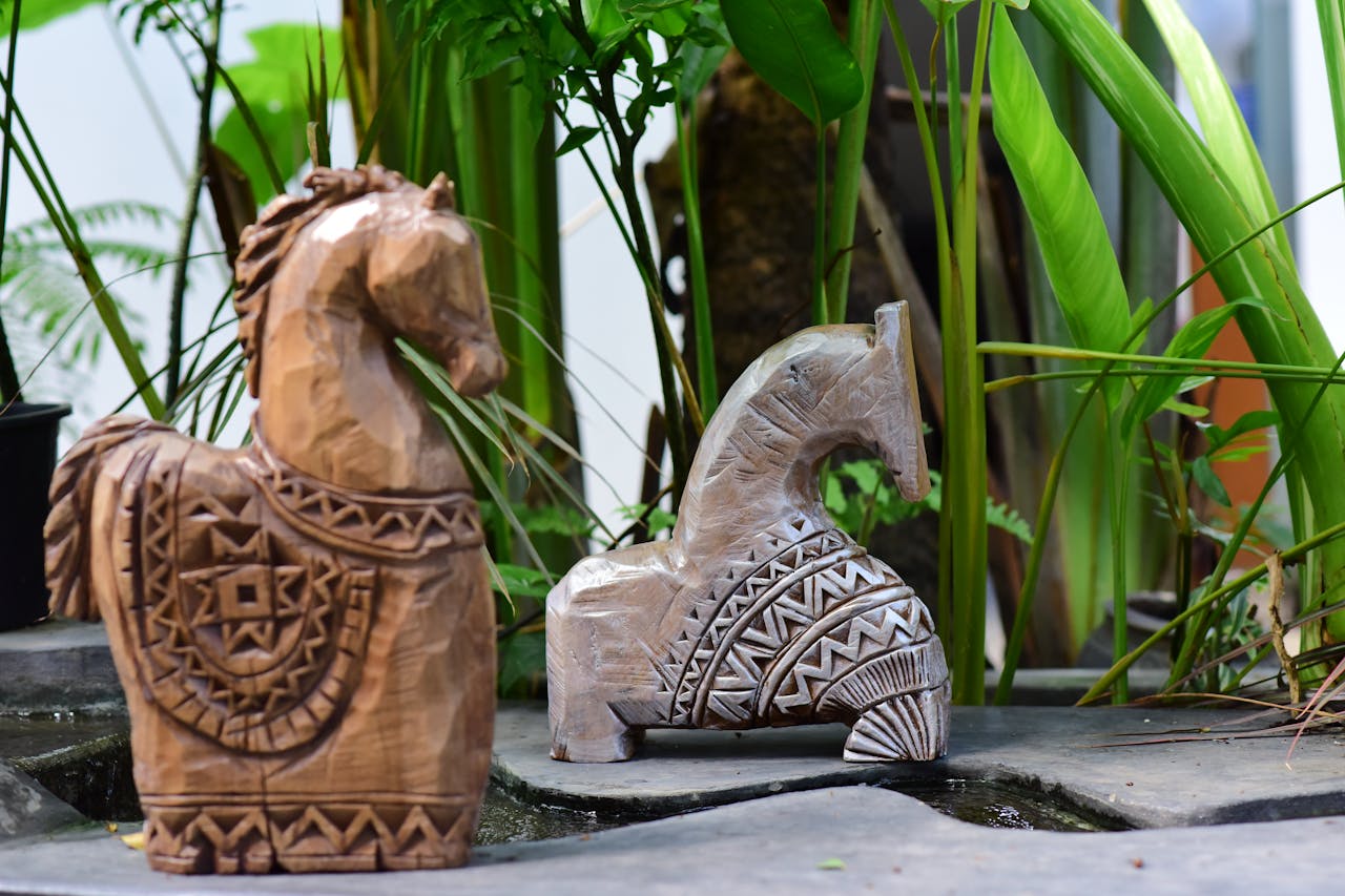 Crafting Captivating Headlines: Your awesome post title goes here Two handcrafted wooden horse sculptures displaying intricate patterns set amidst lush greenery.
